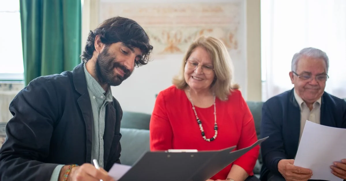 Un consultant assiste des clients âgés dans un cadre moderne, signant des documents ensemble.