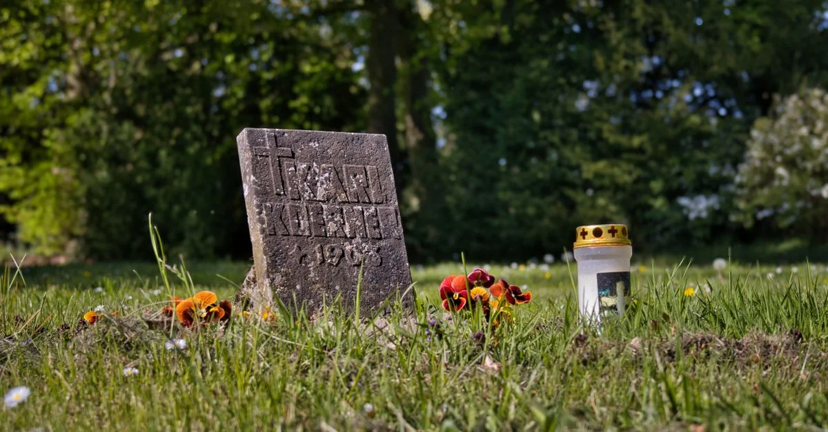 Une scène paisible de cimetière montrant une pierre tombale, des fleurs et une bougie.