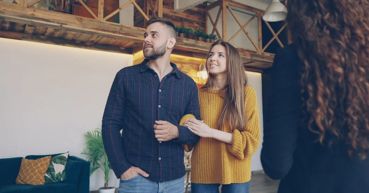 Un couple heureux visitant un appartement moderne avec une décoration stylée et de la lumière naturelle.